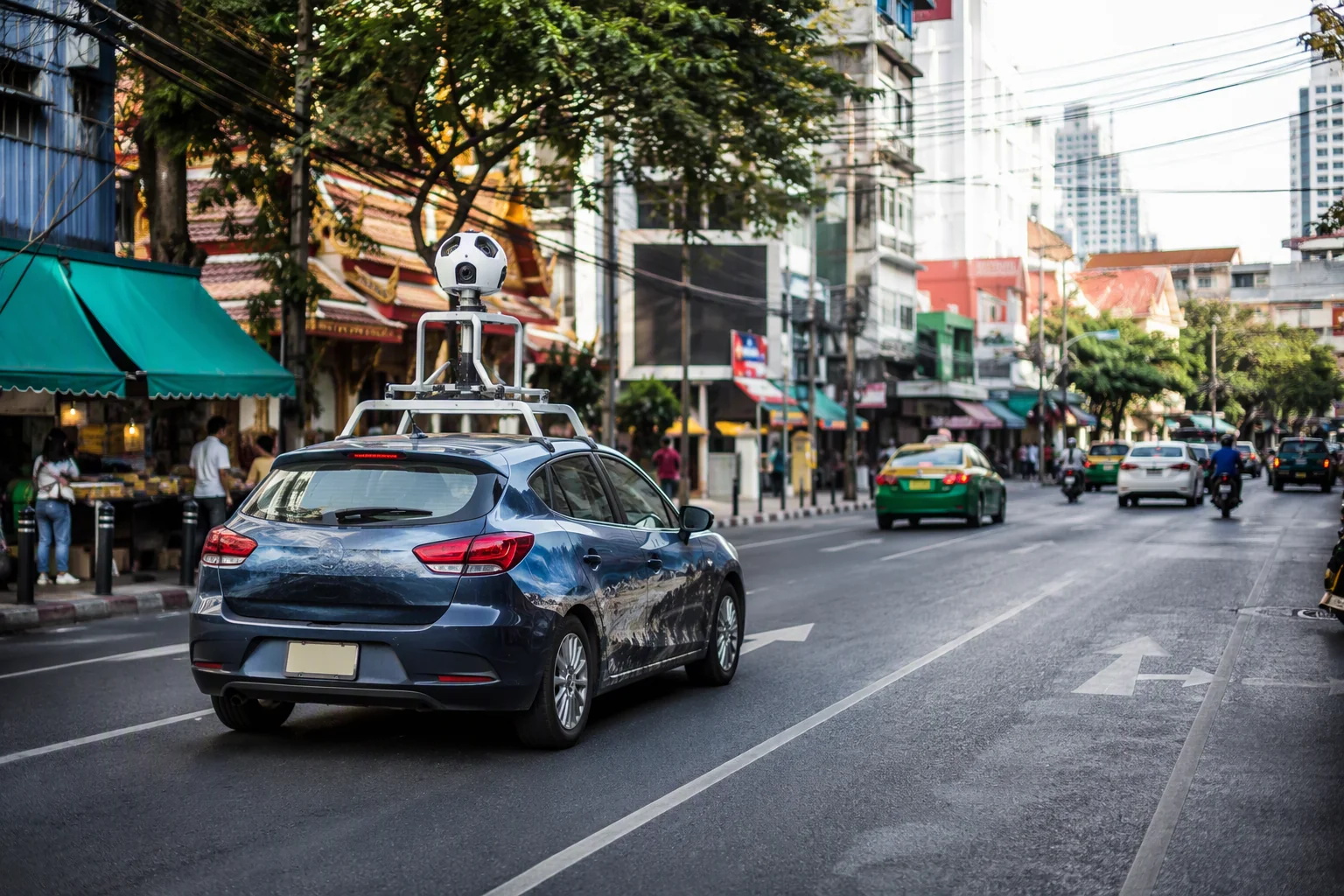 a camera-equipped street-mapping car traveling along a Bangkok-inspired city road
